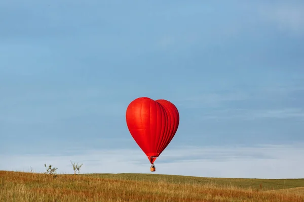 Varmluftsballong i form av hjärta landar på det gröna fältet — Stockfoto