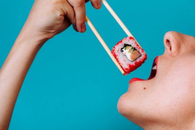 Dudakların makroyu suşi rulosuyla kapat. Japon yemeği yiyen kadın..