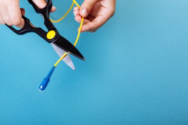 Optik fiberi makasla yok et. Mavi üzerine izole edilmiş.