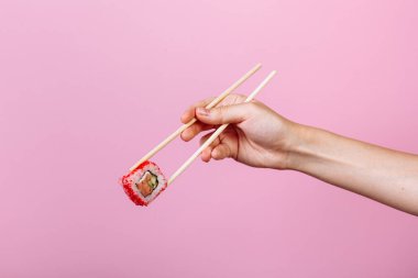 Nefis suşiler California 'yı sarıyor. Pembe arka planda ahşap çubuklar var. Başlık ve metin için yer