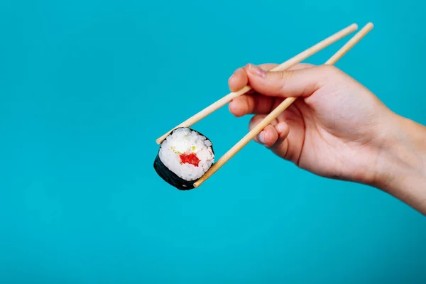 Maki de rolo de sushi saboroso com pauzinhos de madeira no fundo azul perto. Lugar para legenda e texto — Fotografia de Stock