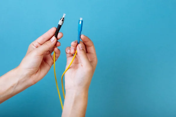 Las manos de las mujeres sostienen SC y FC conector cable de conexión de fibra óptica monomodo sobre fondo azul — Foto de Stock