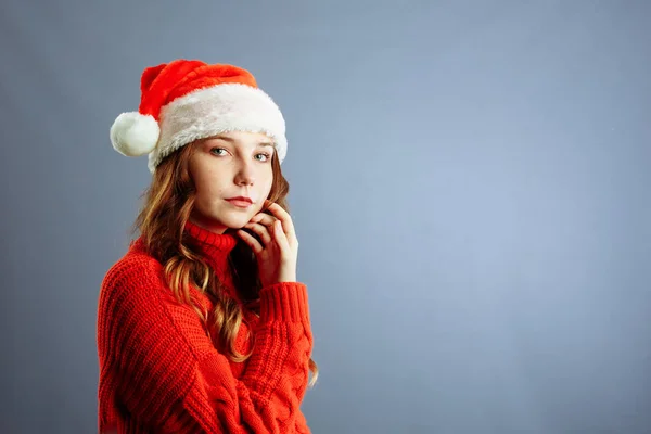 빨간 산타 클라우스 모자를 쓰고 행복하고 신나게 웃는 아름다운 여인의 모습. 고립되어 있는 회색 배경 — 스톡 사진