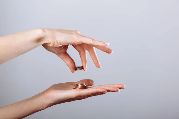 Womans hand giving or taking golden coin to another hand on isolated white background, crisis concept — Stock Photo, Image