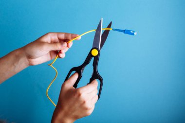 Optik fiberi makasla yok et. Mavi üzerine izole edilmiş..
