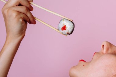 Dudakların makroyu suşi rulosuyla kapat. Japon yemeği yiyen kadın..