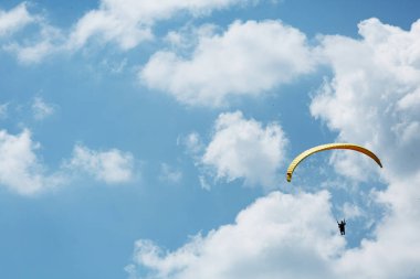 Mavi Paraglider, güneşli bir günde bulutlarla gökyüzüne uçan bir turist ile ikili eğitmen..