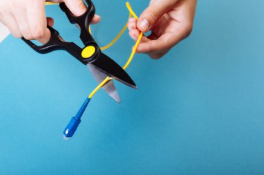 Optik fiberi makasla yok et. Mavi üzerine izole edilmiş.