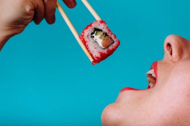 Dudakların makroyu suşi rulosuyla kapat. Japon yemeği yiyen kadın.