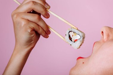 Dudakların makroyu suşi rulosuyla kapat. Japon yemeği yiyen kadın.