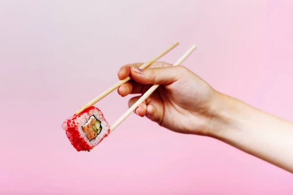 Sabroso rollo de sushi California con palillos de madera sobre fondo rosa de cerca. Lugar para el título y el texto —  Fotos de Stock