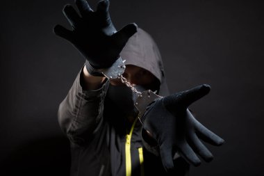 Bilinmeyen, ayırt edilemez bir haydut ya da kelepçeli ve siyah giysili Hucker tutuklandı. Kavram: Kriz nedeniyle suç, siyah arka planda izole edilmiş.