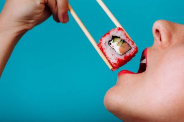 Dudakların makroyu suşi rulosuyla kapat. Japon yemeği yiyen kadın.