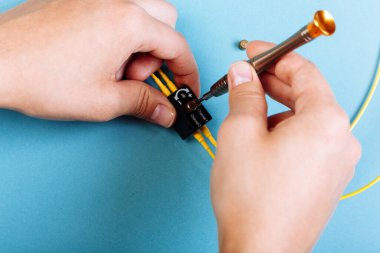 Kadınlar, optik detektörü ayarlamak için tornavida tutarlar. Seçici odaklanma. Mavi arkaplan