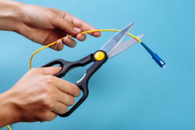 Optik fiberi makasla yok et. Mavi üzerine izole edilmiş..