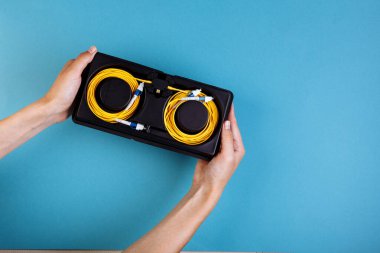 Kadın elleri mavi arka planda mavi değişken optik zayıflatıcıyı tutar.