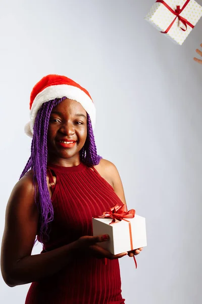 Krásná afro americká žena chytá padající dárky, dívá se na kameru a usmívá se, izolované na bílém pozadí — Stock fotografie