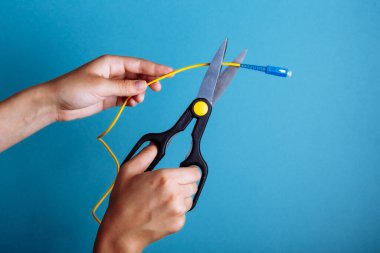 Optik fiberi makasla yok et. Mavi üzerine izole edilmiş.