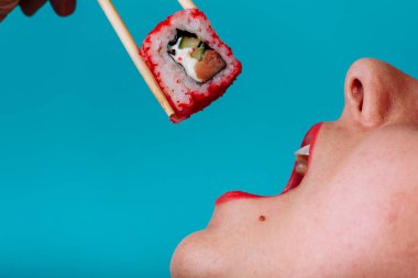 Dudakların makroyu suşi rulosuyla kapat. Japon yemeği yiyen kadın..