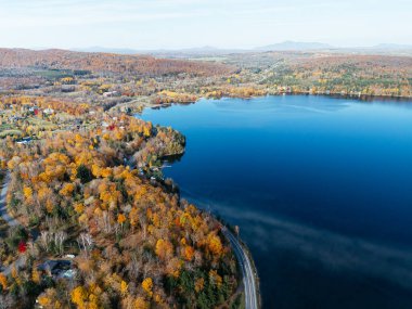 Kanada 'da yerleşim binaları ve sonbahar ormanları olan dolambaçlı bir göl yolu insansız hava aracı. g.