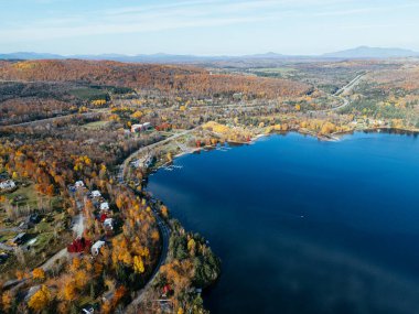 Kanada 'da yerleşim binaları ve sonbahar ormanları olan dolambaçlı bir göl yolu insansız hava aracı. g.