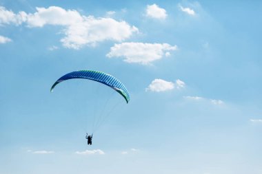 Mavi Paraglider güneşli bir günde bulutlarla gökyüzüne uçuyor..