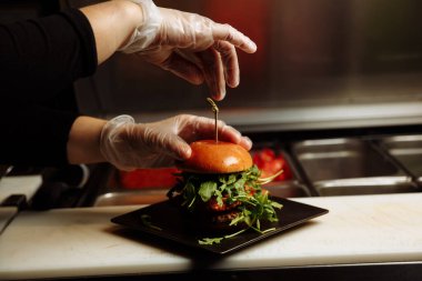 Şef, restoranın mutfağında sebze bazlı roka ve roka ile vejetaryen burger hazırlıyor. g.