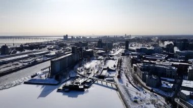 Montreal Eski Limanı 'nın kış manzarası ve şehrin ufuk çizgisi ve liman altyapısı ile donmuş St. Lawrence Nehri. g.