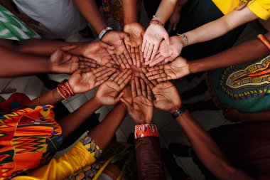 Çok uluslu bir grup insanın elleri havada: Afrika, Latin Amerika ve Avrupa halkı bir çember içinde bir arada..