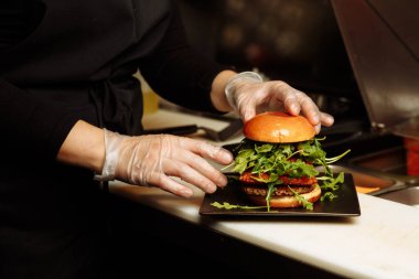 Şef, restoranın mutfağında sebze bazlı roka ve roka ile vejetaryen burger hazırlıyor. g.