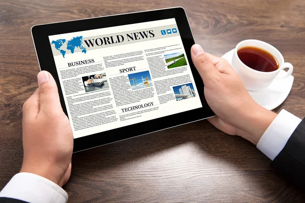 businessman holding tablet computer with world news site on scre