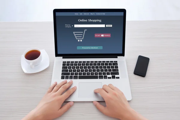 Mandlige hænder i notesbog tastatur med online shopping på skærmen - Stock-foto