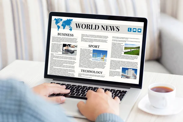 Man holding notebook with world news site on the screen — Stock Photo, Image