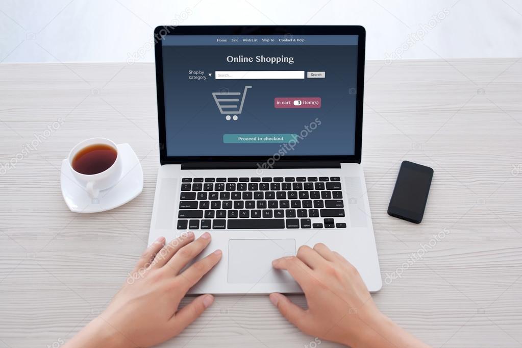 male hands in notebook keyboard with online shopping on screen