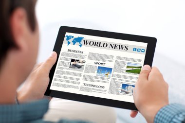 adam holding tablet ile dünya haber sitesi bir ekranda
