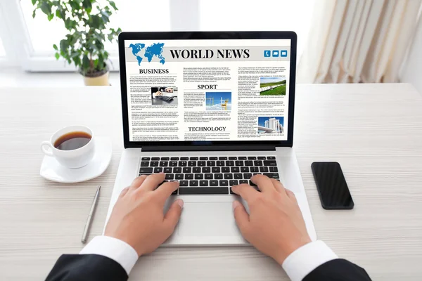 Бизнесмен держит ноутбук с мировым новостным сайтом на экране — стоковое фото