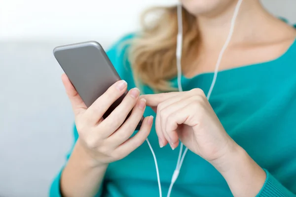 Woman holding a phone and listening to music on headphones — Stock Photo, Image