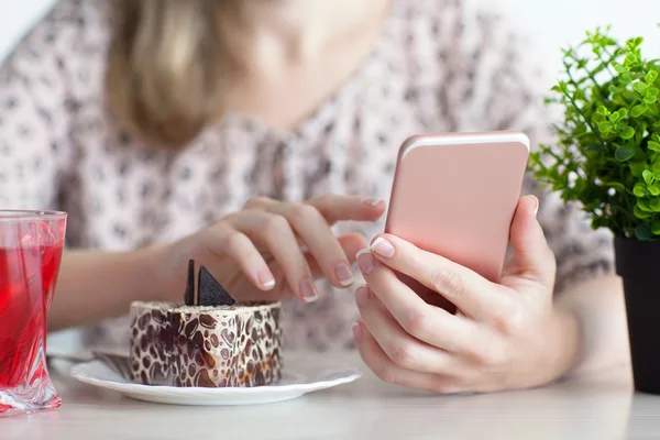 Женщина завтракает в кафе и держит розовый телефон — стоковое фото