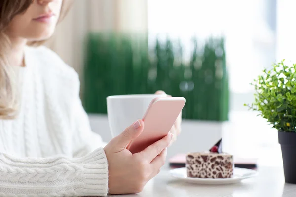 Mujer en la cafetería bebiendo café y sosteniendo el teléfono rosa —  Fotos de Stock