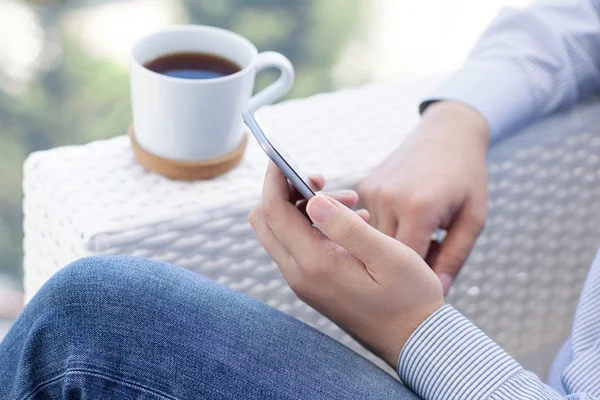 Mann sitzt im Sommercafé und trinkt Tee und hält Telefon — Stockfoto