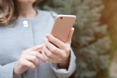 Kadın sokakta bir pembe telefon tutarak