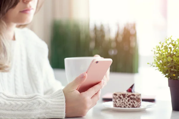 Mujer en la cafetería bebiendo caffee y sosteniendo teléfono rosa —  Fotos de Stock