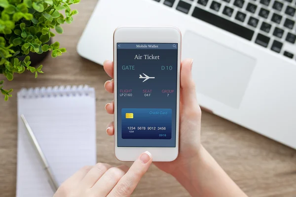 Female hand holding phone with online air ticket and notebook — Stock Photo, Image