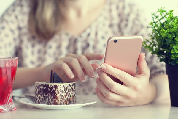 Женщина завтракает в кафе и держит розовый телефон — стоковое фото