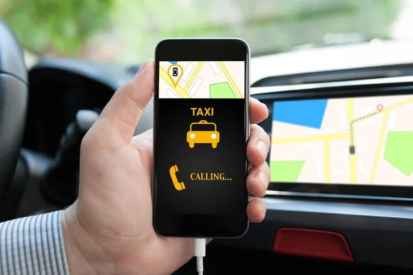 Człowiek w samochodzie, trzymając telefon z aplikacji taxi na ekranie — Zdjęcie stockowe