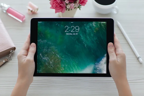 Mujer sosteniendo iPad Pro Espacio Gris con fondo de pantalla IOS 10 —  Fotos de Stock