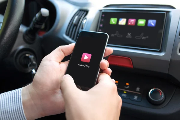 Man hand in car holding phone with Auto Play multimedia — Stock Photo, Image