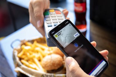 Alanya, Türkiye - 13 Ekim 2020: Elde tutulan iPhone 11 ve ekranda Apple Pay ve online geçiş terminali burger
