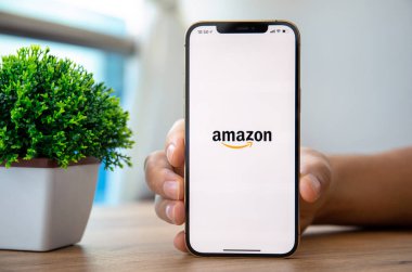 Alanya, Türkiye - 26 Kasım 2020: iPhone 12 Pro Max Gold ile çevrimiçi internet alışveriş servisi Amazon 'u elinde tutan adam ekranda.