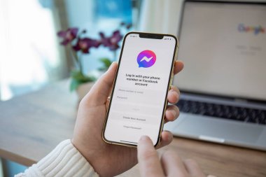 Alanya, Türkiye - 16 Aralık 2020: İnsan eli iPhone 12 Pro Max Gold ve sosyal ağ hizmetleri kuryesi Facebook ekranda